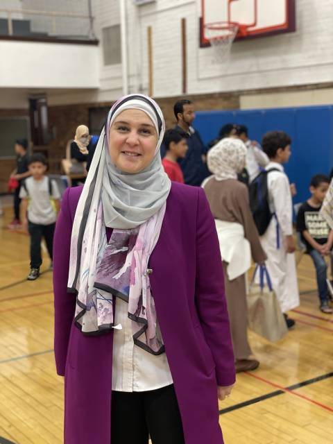 C-ASSIST chief operating officer Zeina Berry smiling while wearing a gray hijab and purple sweater in a gymnasium