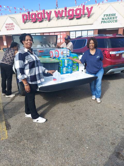 Two women stand outside a piggly wiggly with water