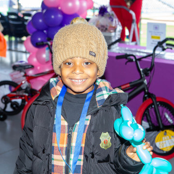 Child smiling holding a balloon animal