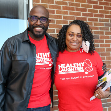 Two people smiling and wearing Healthy Laughter shirts