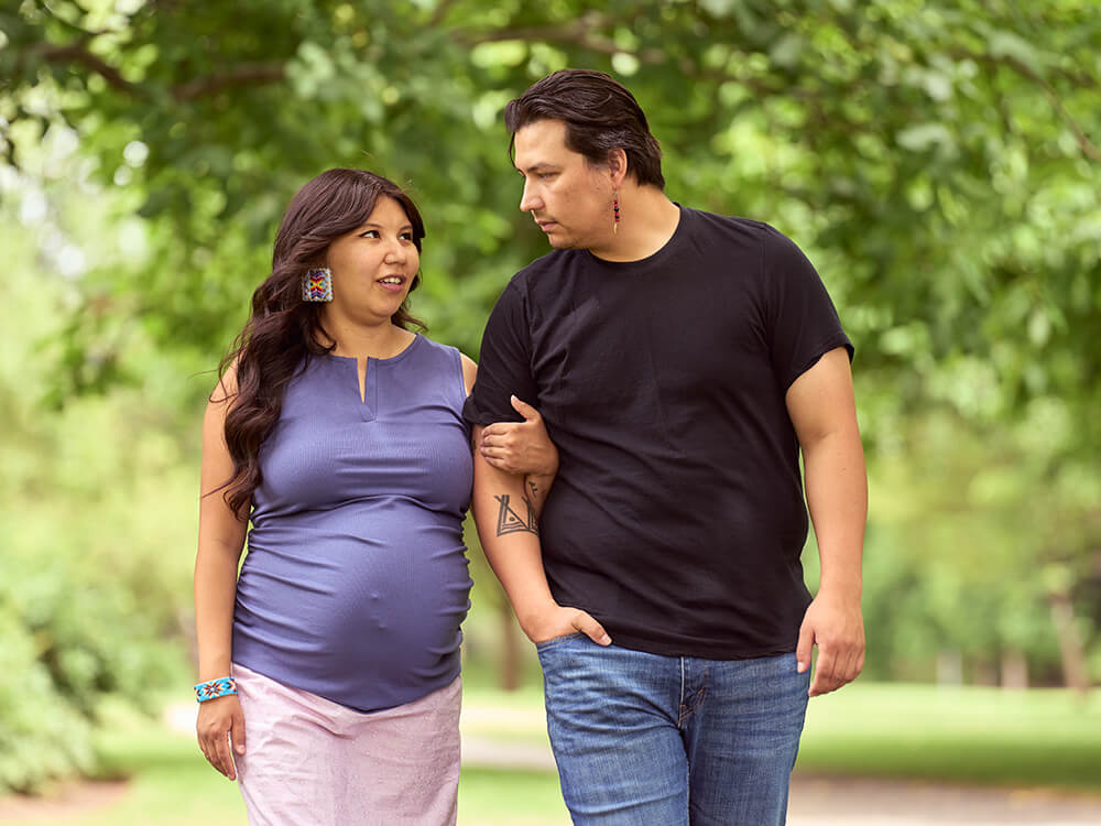 A pregnant person walking while holding the arm of another person