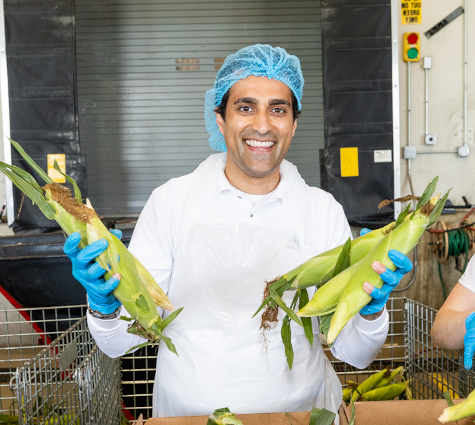 A smiling man in a hairnet holding corn