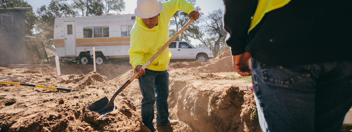 Worker using a shovel standing in a ditch