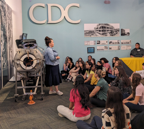 Seated students listening to guide describe the CDC's history at the Disease Detective Camp