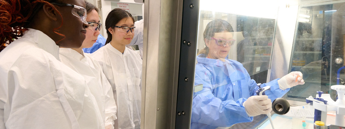 An instructor demonstrating lab equipment to a group of students