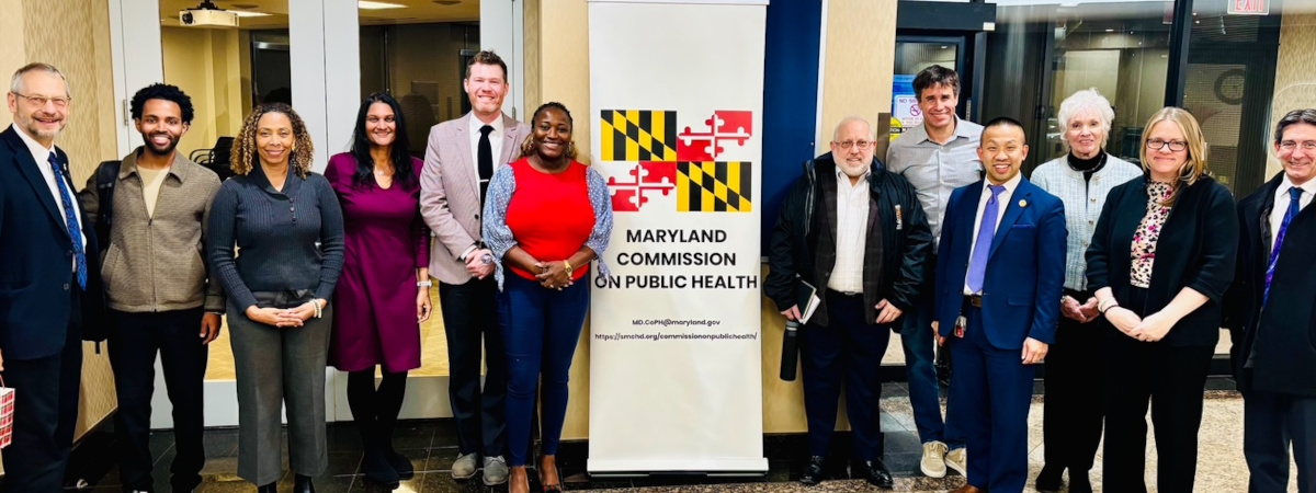 A group of people posing beside a banner for the Maryland Commission on Public Health