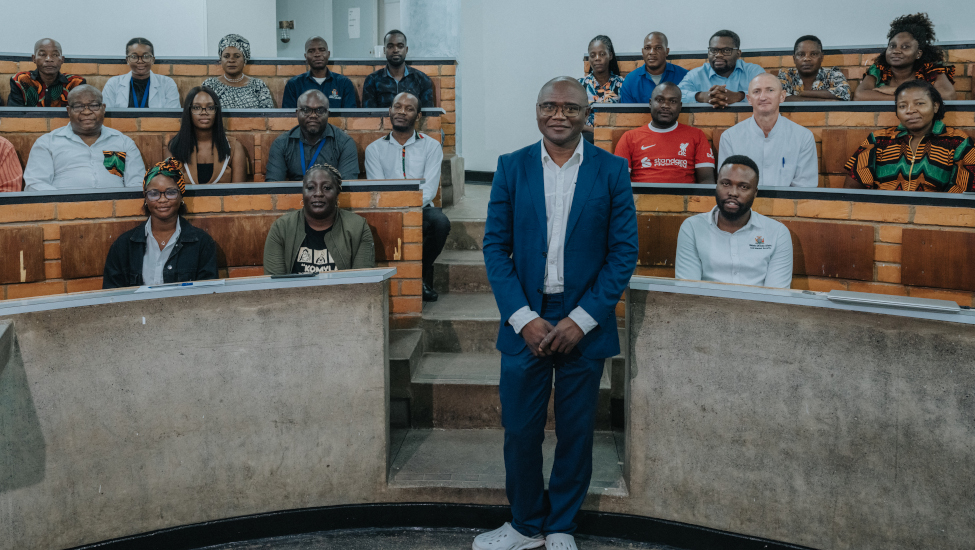 Dr. Luchenga Adam Mucheleng’anga posed in an auditorium before seated staff
