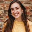 A woman in a yellow shirt smiles for the camera