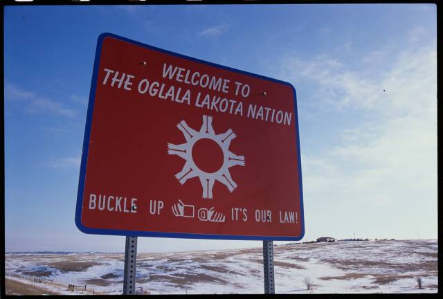 A large red sign says "Welcome to the Oglala Lakota Nation