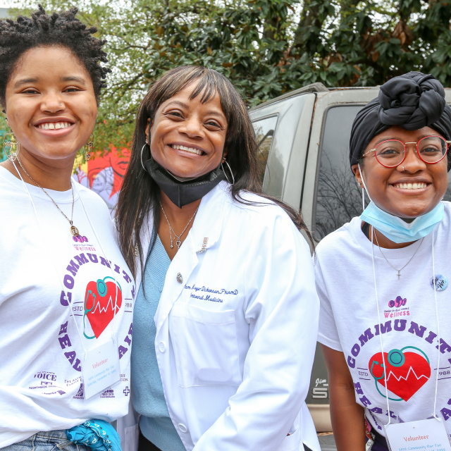 Three women from the Center for Black Women's Wellness smile for the camera at an annual health fair