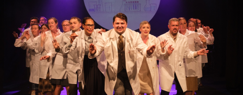 a professional photo from a performance of "The Mold That Changed the World," of a group of singing and dancing scientists