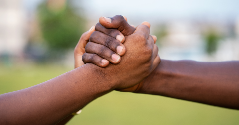 Two hands of African American people are holding against a blurry background