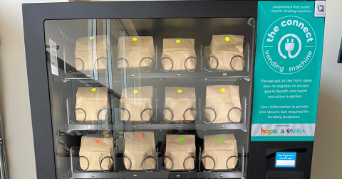A vending machine is filled with brown paper bags. A teal sign says this is "the connect vending machine."