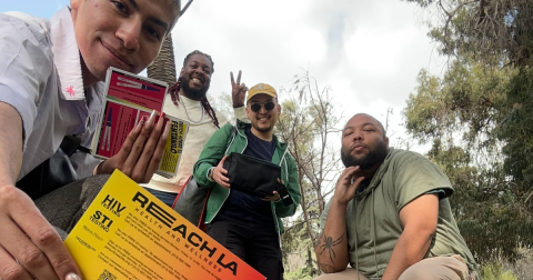 A group of people pose for a photo holding a flyer for REACH LA