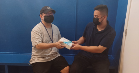 Two men in black face masks hold an HIV self-testing kit.