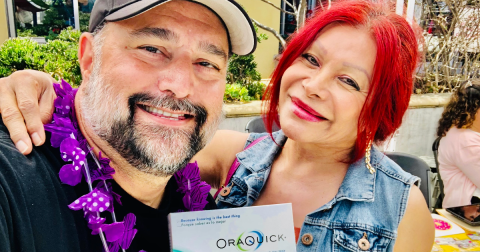 A man and woman with red hair pose together with an HIV self-testing kit.
