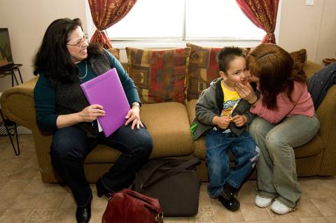 Family Coach Yolanda Tapia looks on as Cecelia Reynosa kisses her three-year-old son Kevin Alexis at their home in Kansas City, Kansas.